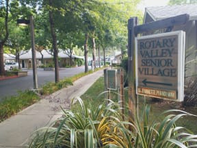 a sign for rotary valley senior village on the side of a sidewalk