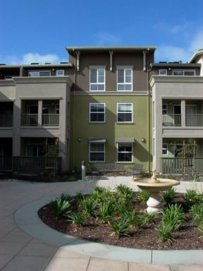 an outdoor courtyard with a fountain in front of an apartment building