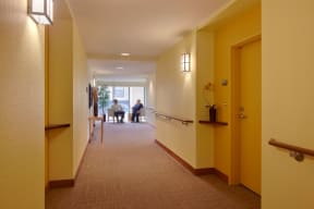 a long hallway with people sitting in a room at the end