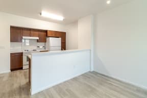 an empty living room with a white wall and a kitchen