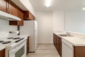 an empty kitchen with white appliances and wooden cabinets