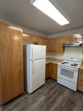 a kitchen with a white stove and refrigerator and wooden cabinets