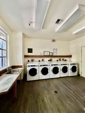 a laundry room with four washing machines and a sink