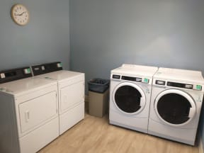 a laundry room with four washing machines and a clock on the wall