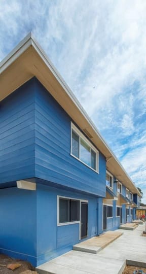 a blue building with a peaked roof and a sidewalk