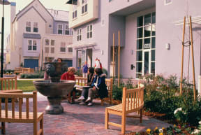 a group of people sitting around a table in a courtyard