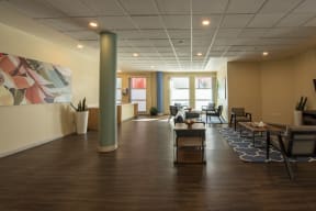 a large lobby with chairs and tables and a large painting on the wall