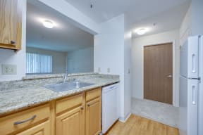 a kitchen with granite counter tops and wooden cabinets and a refrigerator