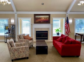 a living room with a red couch and chairs and a fireplace