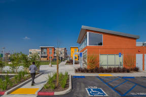 a man walking in front of a building with a parking lot