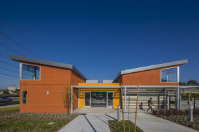 a modern orange building with a sidewalk in front of it