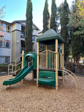 a playground with a slide and a pavilion in front of a building