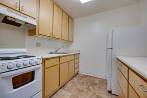 an empty kitchen with white appliances and wooden cabinets