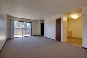 an empty living room with a sliding glass door to a balcony