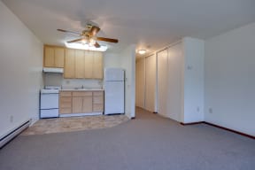an empty living room and kitchen with a ceiling fan