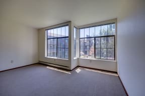 an empty living room with large windows and carpeting