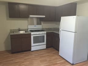 an empty kitchen with white appliances and brown cabinets