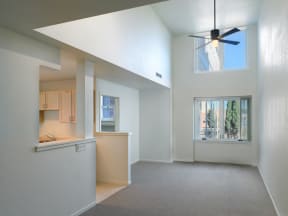 an empty living room with a kitchen and a ceiling fan