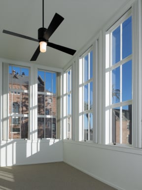 a living room with large windows and a ceiling fan