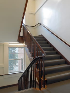 a staircase in a building with a wooden railing and a window