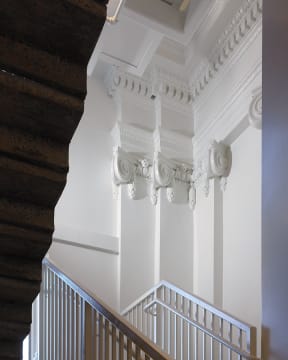 a view of the top of a staircase in a building with white ceilings and columns