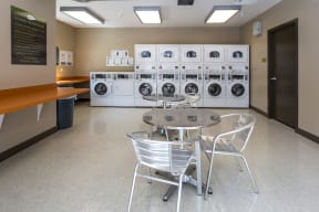 a table and chairs in a laundry room with washing machines
