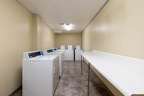 A row of washing machines are lined up in a laundry room.