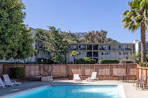 A pool surrounded by a wooden fence and chairs.