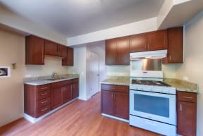 an empty kitchen with wooden cabinets and a white stove and oven