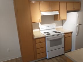 an empty kitchen with white appliances and wooden cabinets