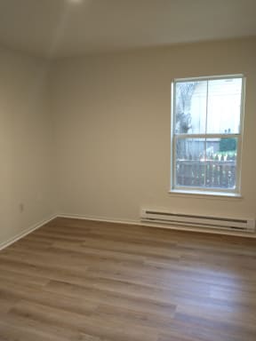 an empty room with a window and wooden floors