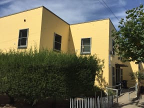 a yellow house with a hedge in front of it