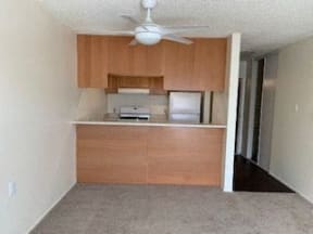 an empty kitchen with wooden cabinets and a ceiling fan