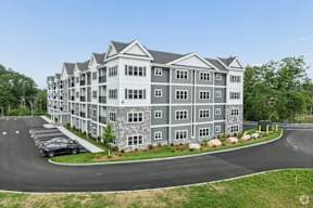 A large, modern apartment building with a parking lot in front.
