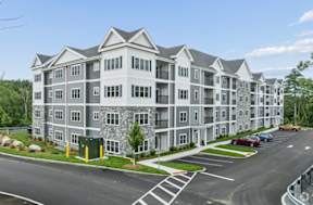 A large, modern apartment building with a parking lot in front.