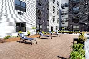 A patio with a bench and a building in the background.
