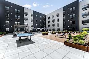 A courtyard with a table tennis table and benches surrounded by buildings.