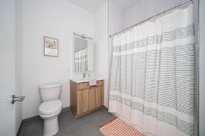 A bathroom with a toilet, sink, and shower curtain.at Art Of Newark, New Jersey
