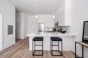 A kitchen with a white counter and bar stools.at Art Of Newark, Newark, 07103