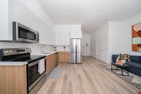 A modern kitchen with wooden cabinets and a stainless steel refrigerator.at Art Of Newark, Newark New Jersey