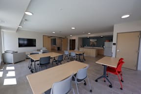 A room with tables and chairs and a television.