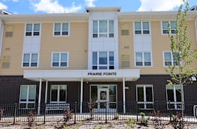 The front of a building named Prairie Pointe with a black fence in front.