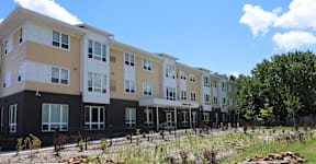 A row of modern apartment buildings with balconies and black railings.