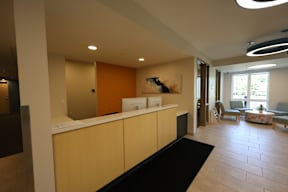 A hallway with a black carpet and a white reception desk.