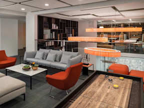 A modern living room with a grey sofa, orange chairs, and a coffee table.