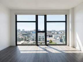 A room with a view of the city through large windows.
