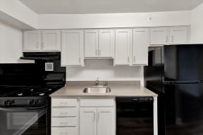 a kitchen with white cabinets and black appliances at Autumn Woods, Bladensburg, MD, 20710