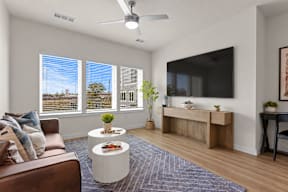 A living room with a brown couch, a white coffee table, and a large window with blinds.