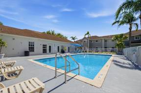 A pool surrounded by sun loungers and a building in the background.