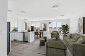 A modern kitchen with a dining table and chairs is adjacent to a living room with a couch and a coffee table.